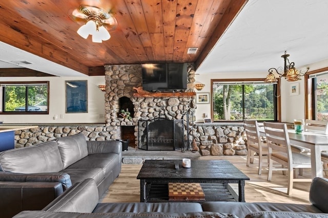 living room featuring light wood-type flooring, a healthy amount of sunlight, and a stone fireplace