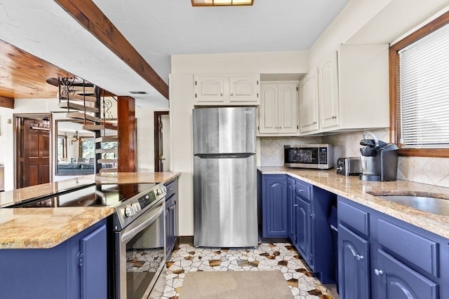 kitchen with blue cabinetry, appliances with stainless steel finishes, tasteful backsplash, light stone counters, and white cabinets