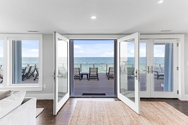 doorway to outside with visible vents, a water view, recessed lighting, wood finished floors, and french doors