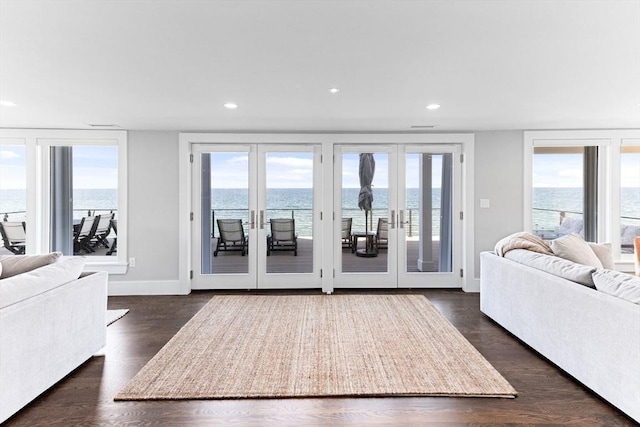 living room with a water view, recessed lighting, and dark wood finished floors