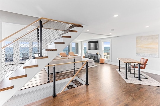 staircase featuring wood finished floors, baseboards, and recessed lighting
