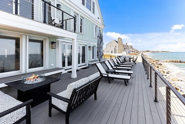 deck featuring a water view, an outdoor fire pit, a beach view, and french doors