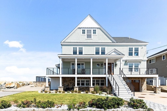 coastal home featuring stairs, stone siding, covered porch, and concrete driveway