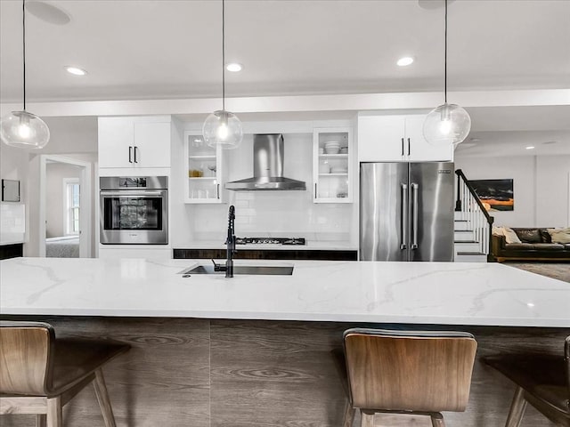 72-74 Grafton St Unit 2, Arlington, MA 02474 - kitchen featuring stainless steel appliances, wall chimney range hood, white cabinetry, glass insert cabinets, and a sink