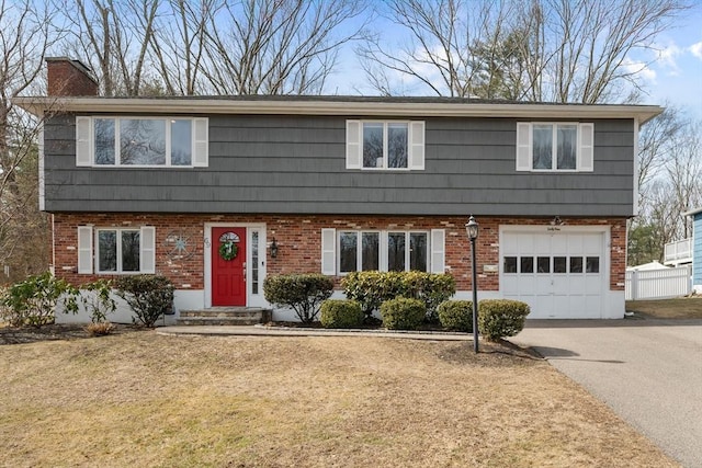 colonial house featuring brick siding, driveway, a chimney, and a garage