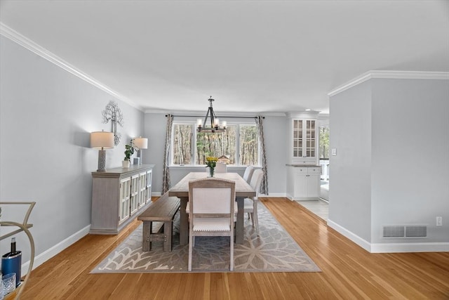 dining area featuring visible vents, light wood-style floors, and ornamental molding