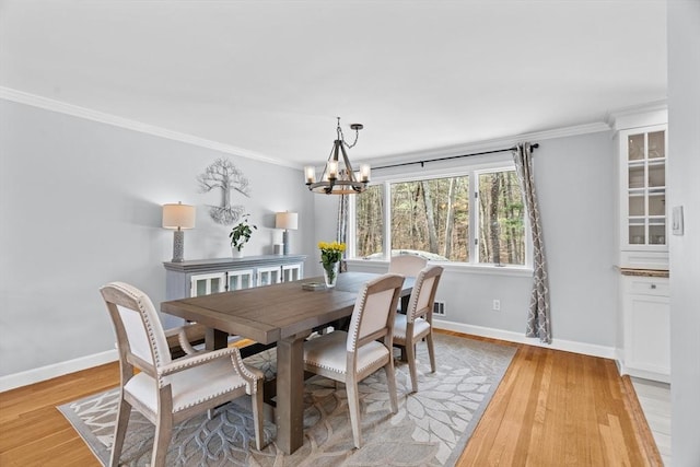 dining area with baseboards, light wood finished floors, and ornamental molding