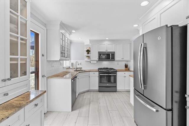 kitchen with backsplash, light stone counters, stainless steel appliances, white cabinetry, and open shelves