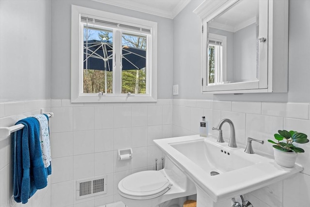 half bath featuring a sink, visible vents, toilet, and a healthy amount of sunlight