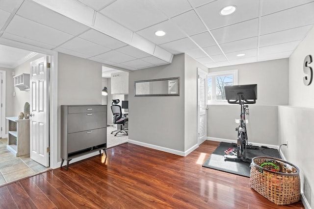 workout area featuring a drop ceiling, recessed lighting, baseboards, and wood finished floors