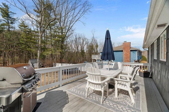 wooden deck with outdoor dining space and grilling area