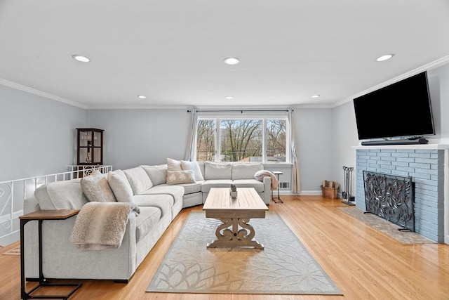 living room featuring crown molding, baseboards, recessed lighting, a fireplace, and light wood-style floors