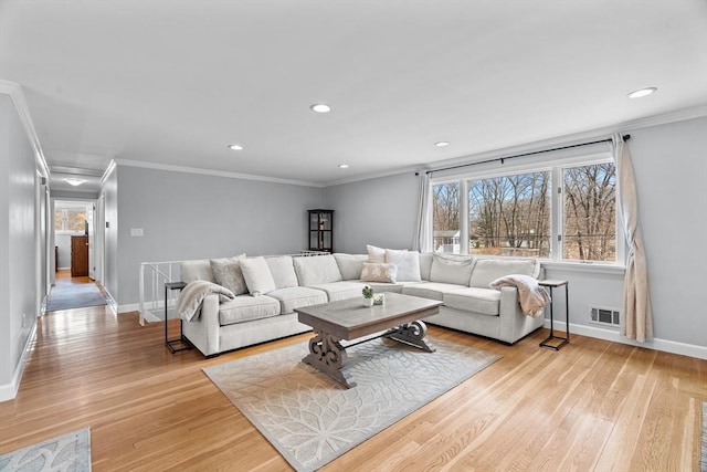 living area featuring visible vents, baseboards, light wood-style floors, and ornamental molding