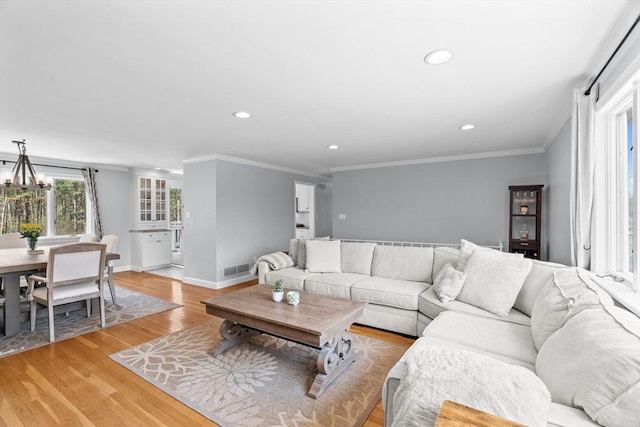 living area with baseboards, recessed lighting, light wood-style floors, crown molding, and a notable chandelier