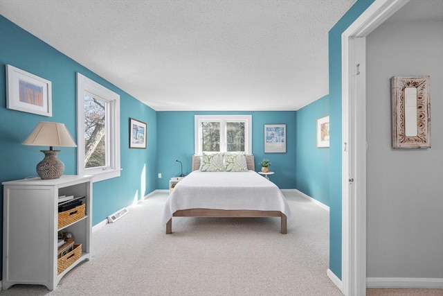 carpeted bedroom featuring multiple windows, a textured ceiling, and baseboards