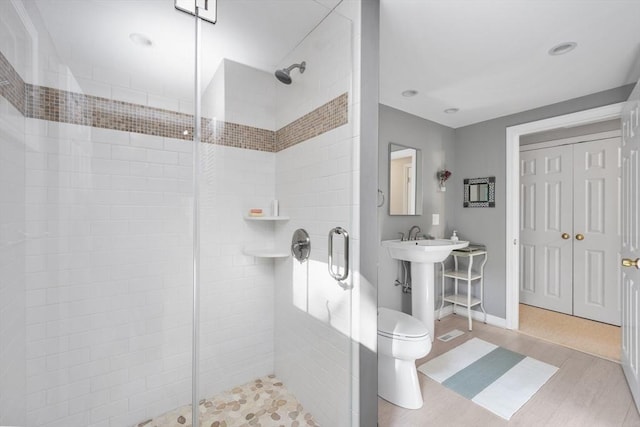 bathroom featuring a stall shower, toilet, and wood finished floors