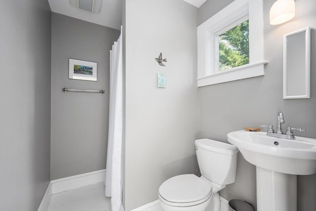 bathroom featuring toilet, baseboards, a sink, and tile patterned floors
