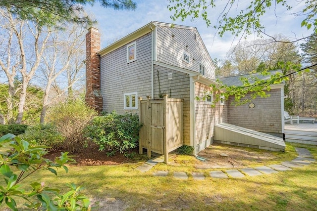 view of side of home with a chimney, a wooden deck, and a yard
