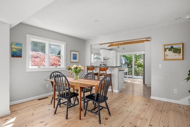 dining area featuring light wood-style flooring and baseboards