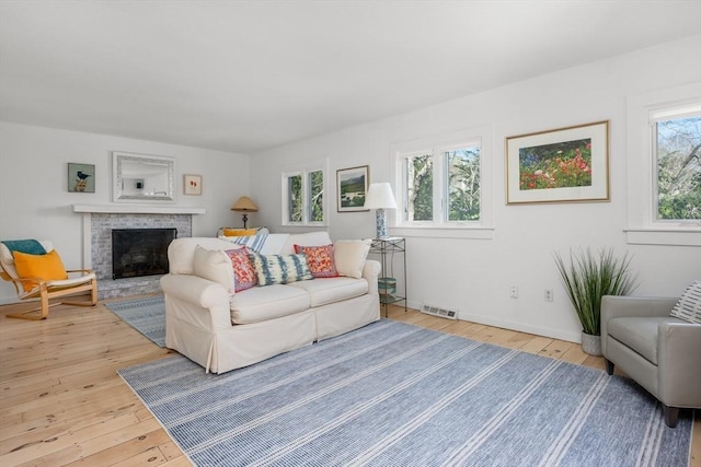 living area featuring light wood finished floors, a fireplace, and baseboards