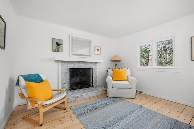 sitting room featuring hardwood / wood-style flooring, a fireplace, and baseboards
