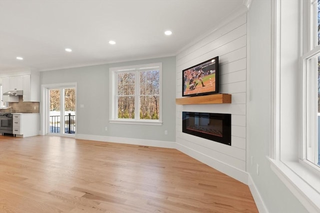 unfurnished living room featuring a large fireplace, crown molding, and light hardwood / wood-style flooring