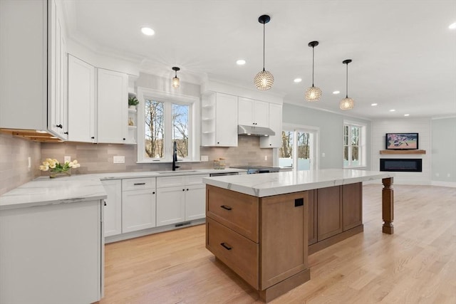 kitchen with sink, white cabinetry, a center island, and light stone countertops