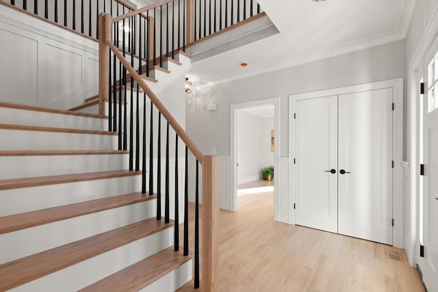 entrance foyer with crown molding and light hardwood / wood-style flooring