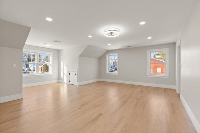 bonus room with light wood-type flooring and vaulted ceiling