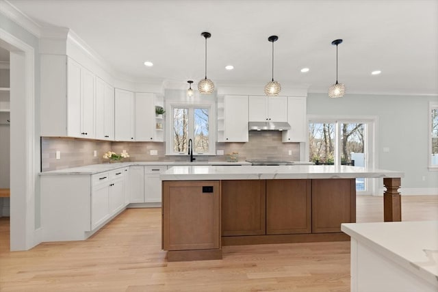 kitchen featuring sink, hanging light fixtures, white cabinetry, and a center island