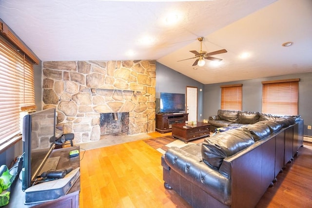 living room featuring ceiling fan, a fireplace, wood finished floors, and vaulted ceiling