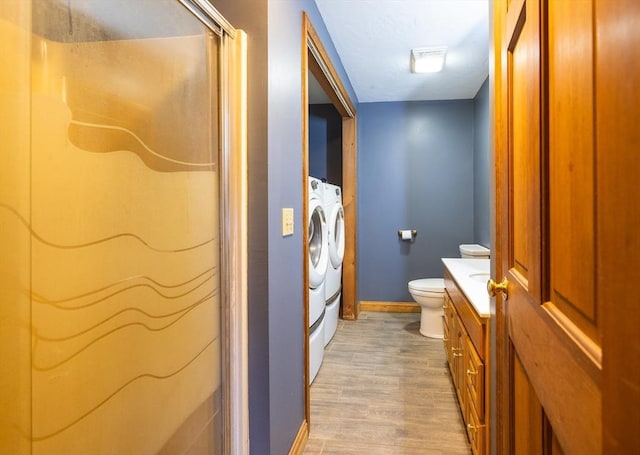 full bathroom featuring a stall shower, washing machine and clothes dryer, baseboards, wood finished floors, and vanity