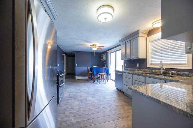 kitchen with freestanding refrigerator, a sink, a ceiling fan, dark stone countertops, and wood finished floors