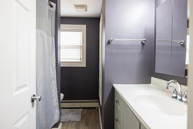 bathroom featuring a baseboard heating unit, wood finished floors, vanity, and baseboards