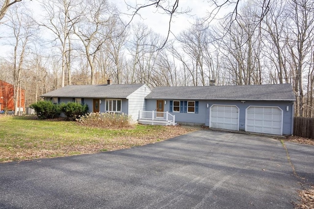 ranch-style home with driveway, a garage, a chimney, and a front lawn