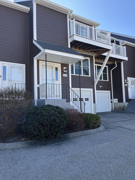 view of front of home featuring an attached garage, a balcony, and driveway