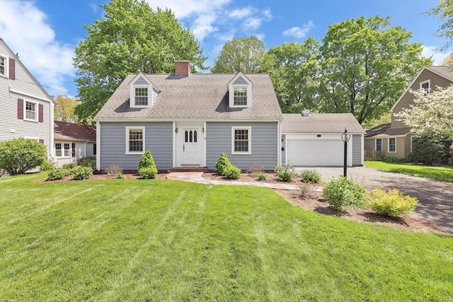 new england style home featuring asphalt driveway, a chimney, a front yard, a garage, and a shingled roof