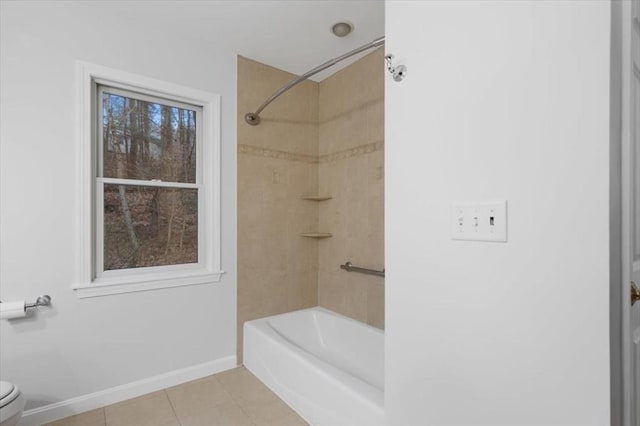 bathroom featuring toilet, tile patterned floors, bathing tub / shower combination, and baseboards