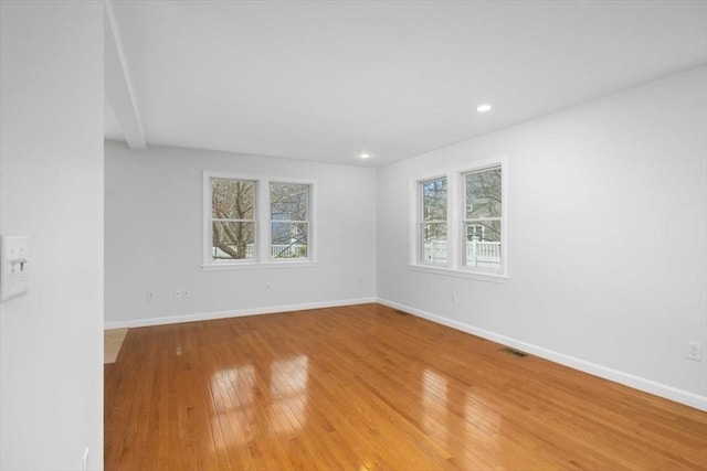 empty room featuring light wood finished floors, baseboards, visible vents, and recessed lighting