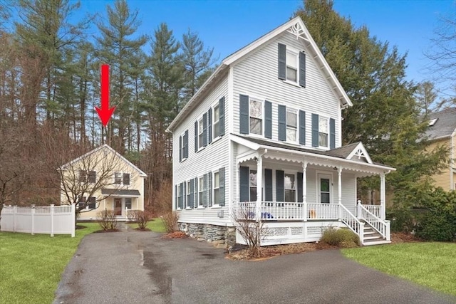 view of front of home with a front yard, fence, and covered porch