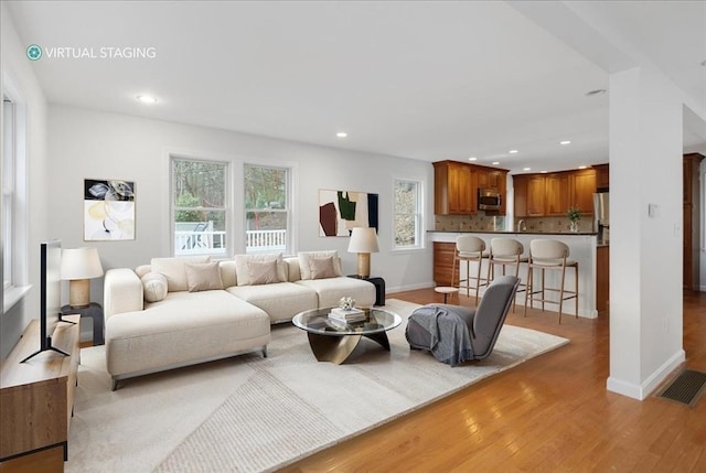 living room with light wood finished floors, baseboards, visible vents, and recessed lighting