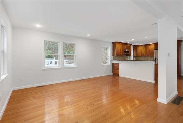 unfurnished living room with recessed lighting, visible vents, light wood-type flooring, and baseboards