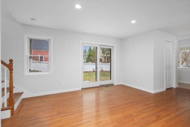 empty room featuring light wood-style floors, stairs, plenty of natural light, and recessed lighting