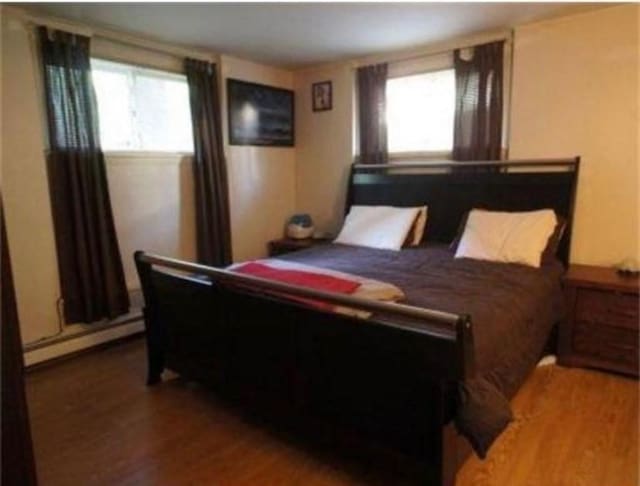 bedroom featuring baseboard heating, multiple windows, and hardwood / wood-style flooring