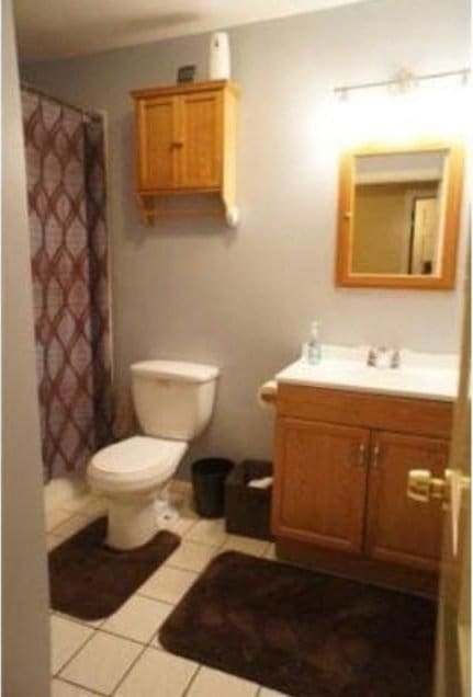 bathroom featuring tile patterned floors, vanity, curtained shower, and toilet