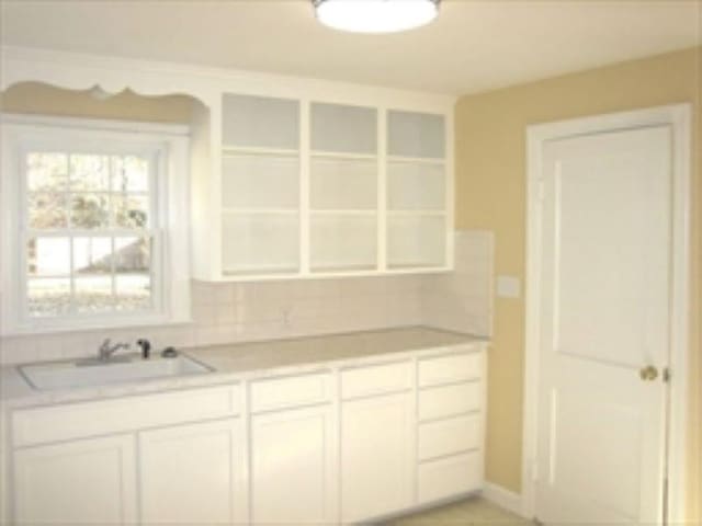 kitchen with light tile patterned flooring, white cabinetry, and sink