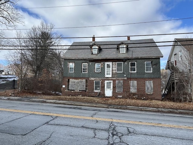 view of front of home featuring brick siding and a chimney