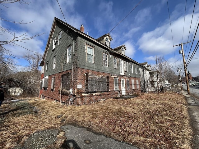 view of property exterior featuring brick siding and a chimney