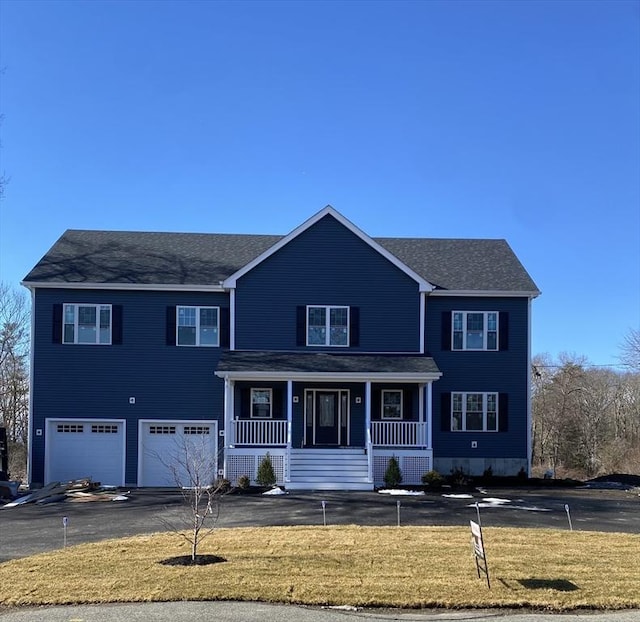 view of front of property with a garage, covered porch, and a front yard