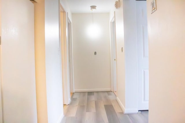 corridor featuring light wood-style flooring and baseboards